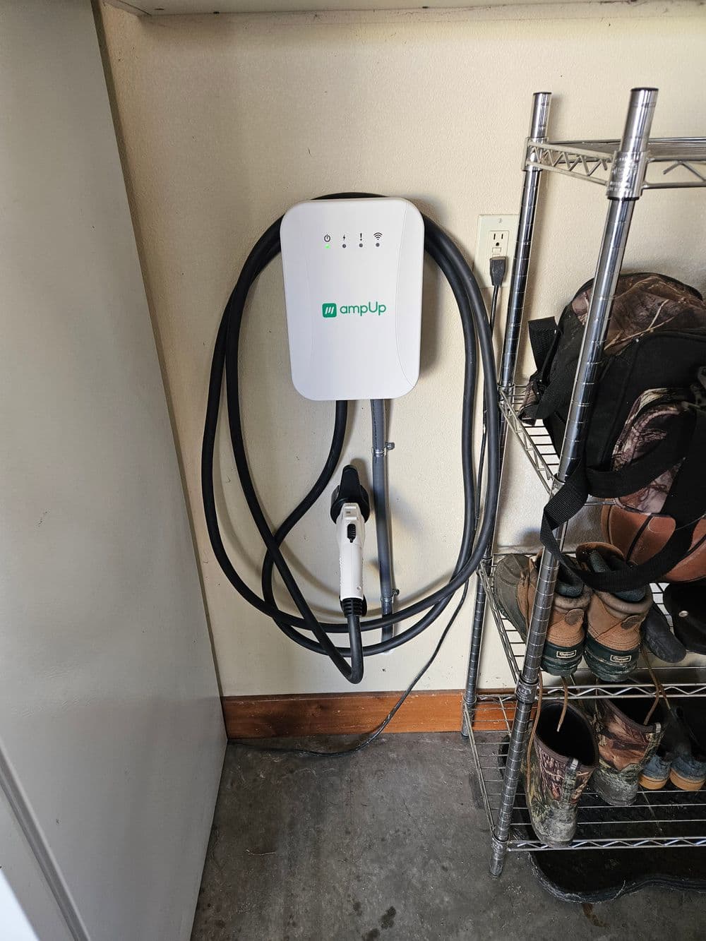 Wall-mounted electric vehicle charger with cable and connector, located in a garage.