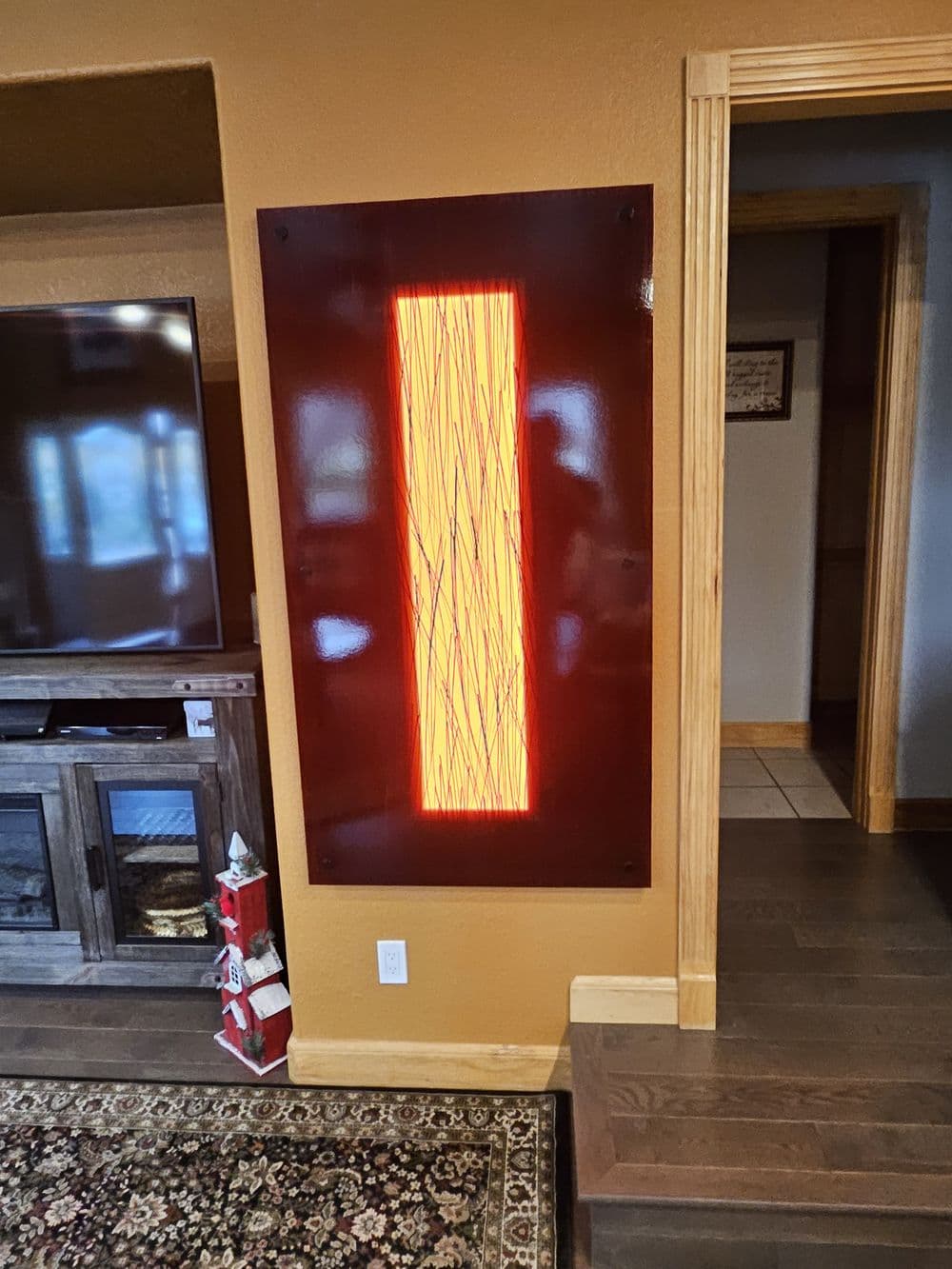 Modern wall art with glowing orange design in a cozy living room setting.