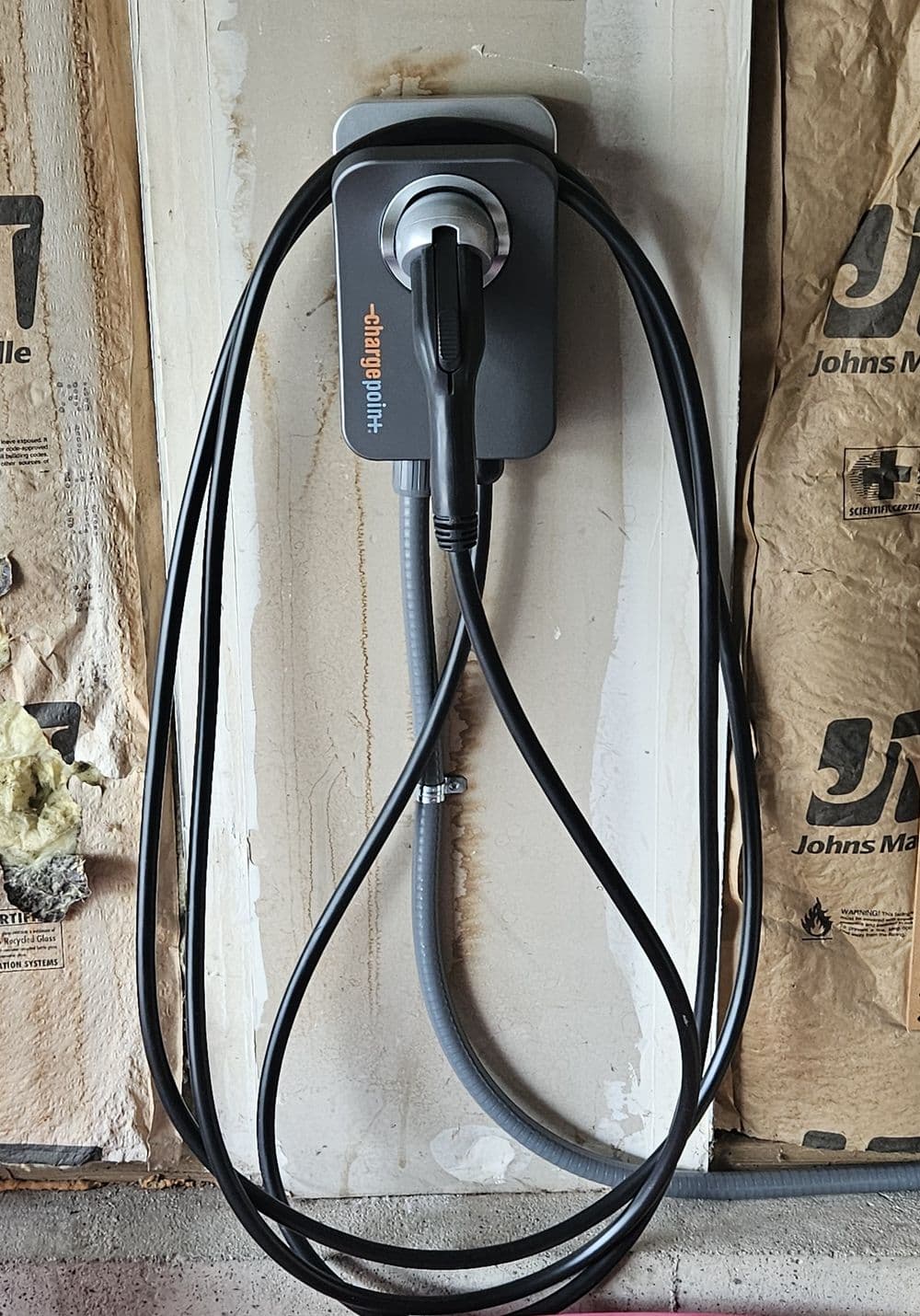 Electric vehicle charging station mounted on a wall with cables neatly arranged.